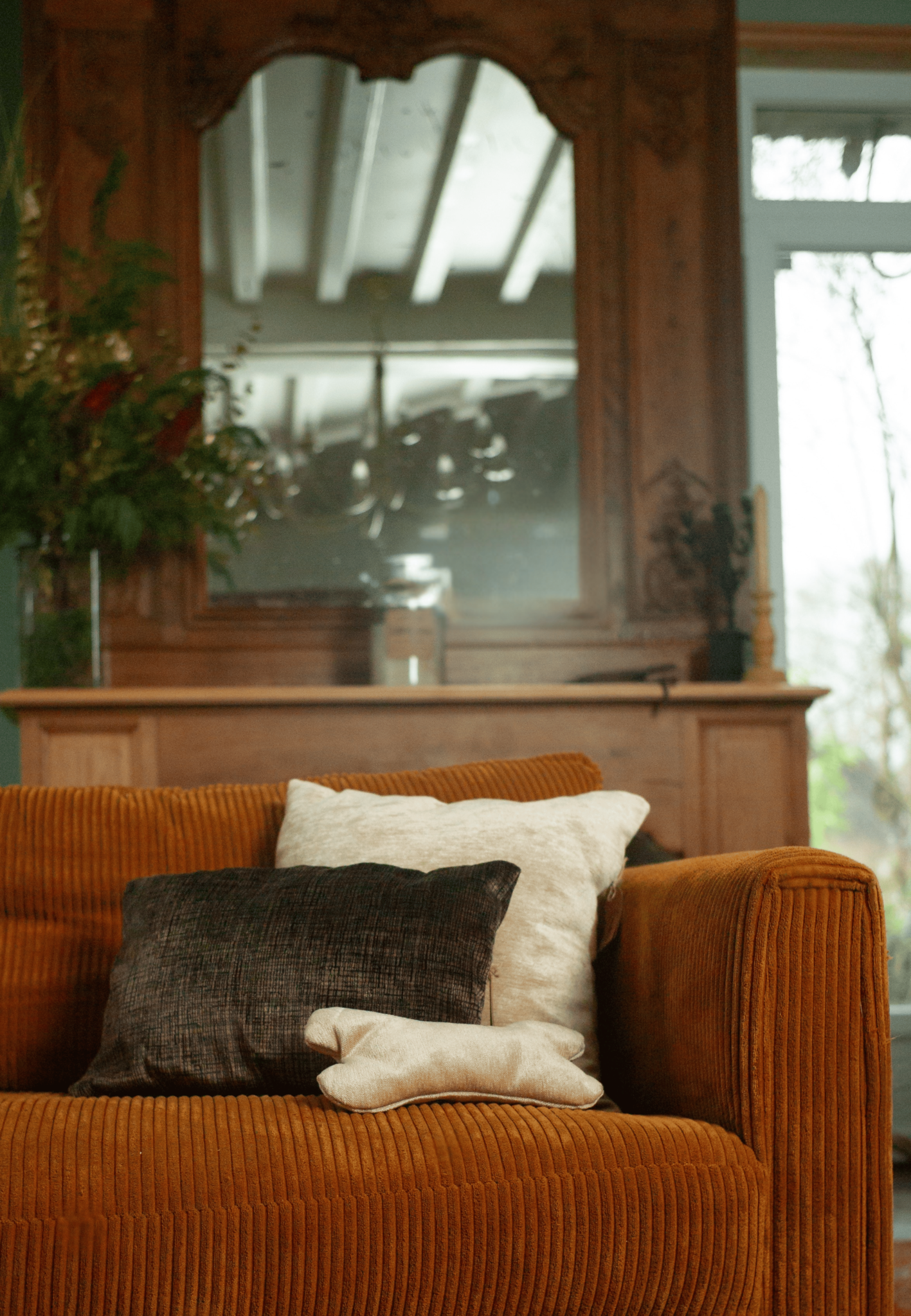 Velvet sofa with decorative brown ivory pillows in living room with wooden furniture