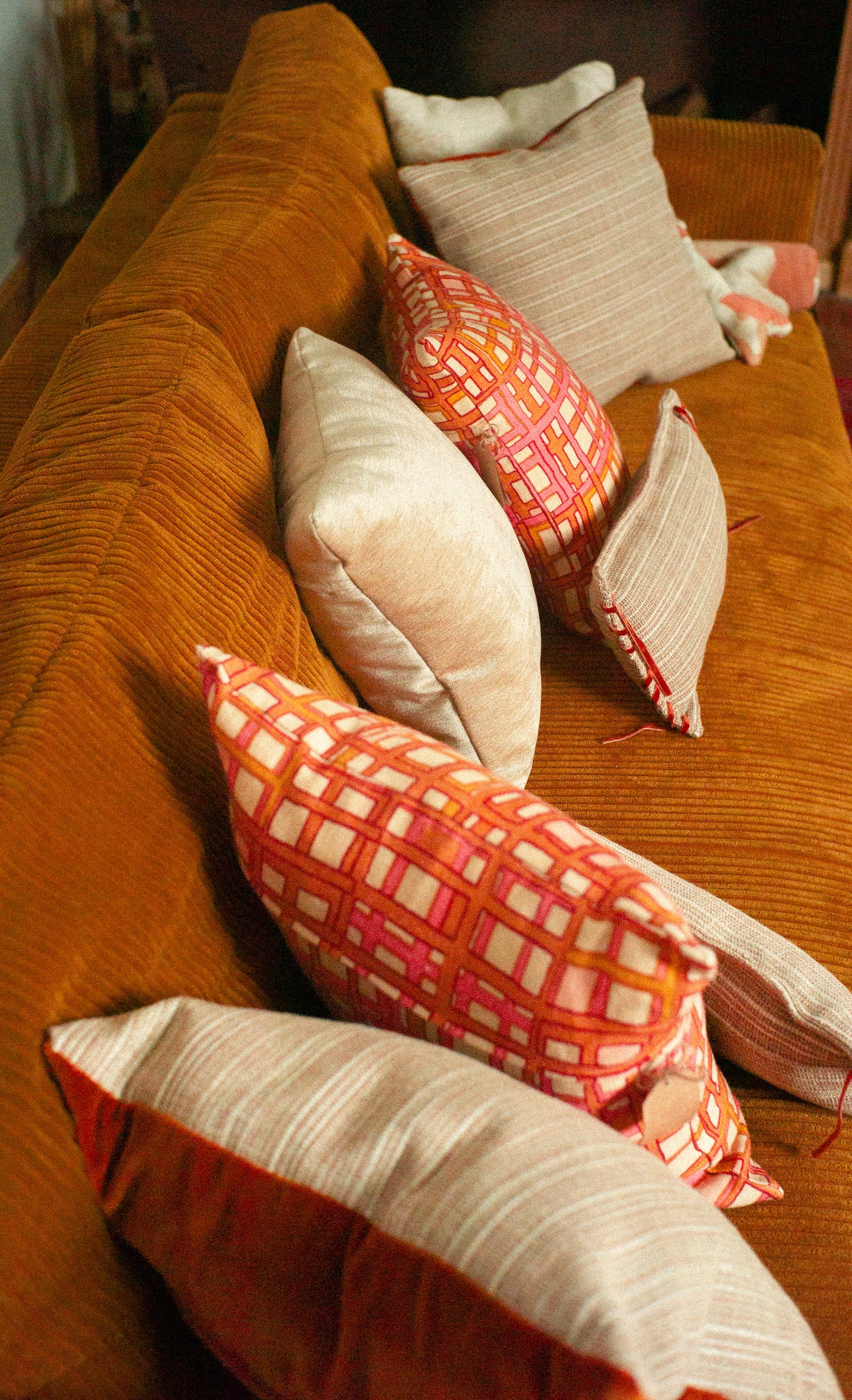 Orange couch with patterned and solid color cushions