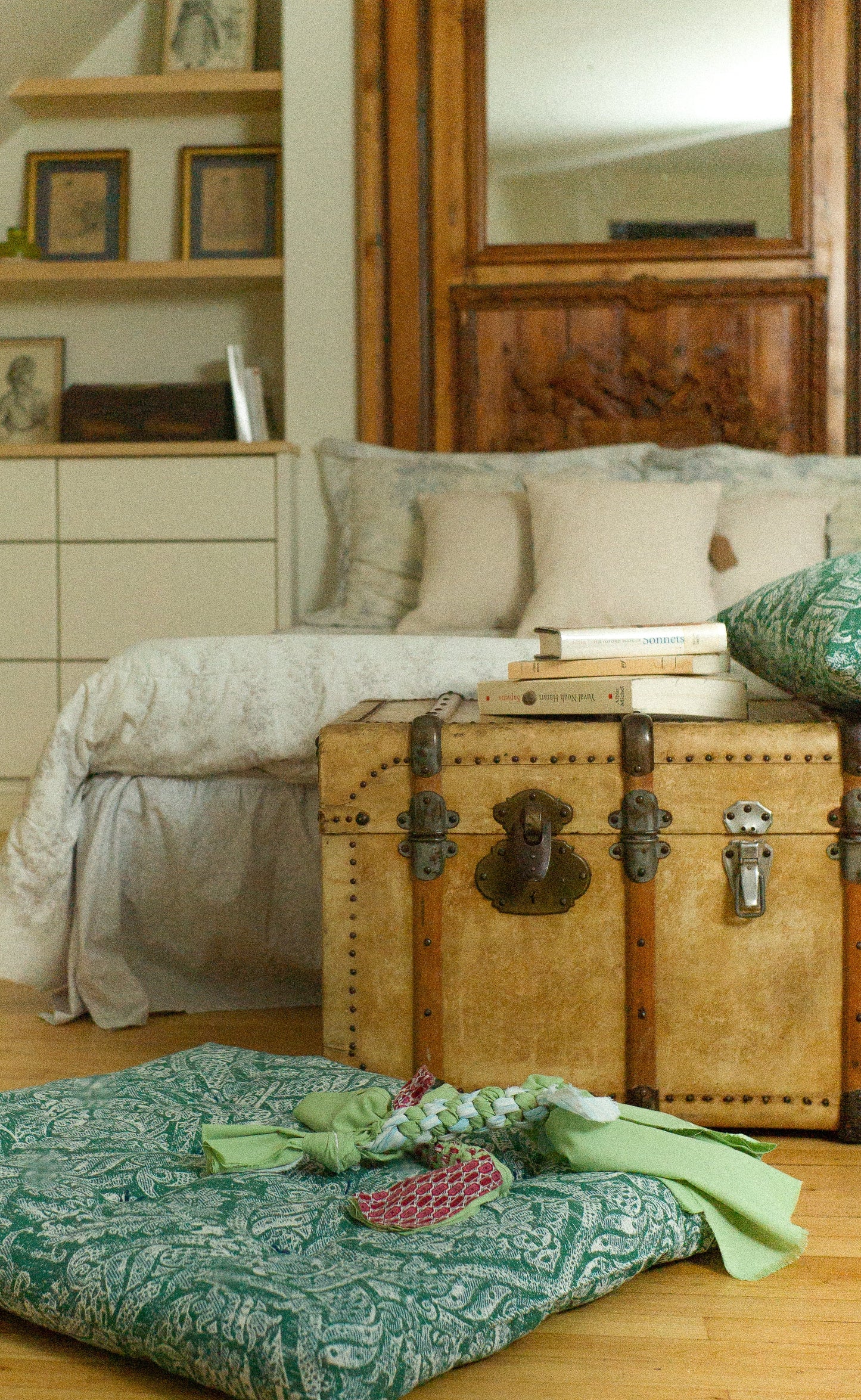 Room interior with a bed, vintage trunk, and decorative pillows.