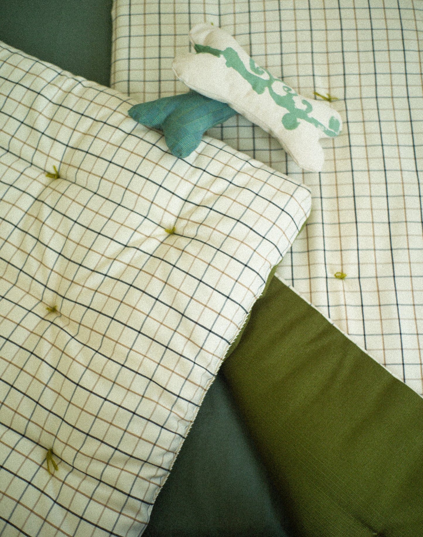 Plaid blanket and pillow on a checkered bedspread