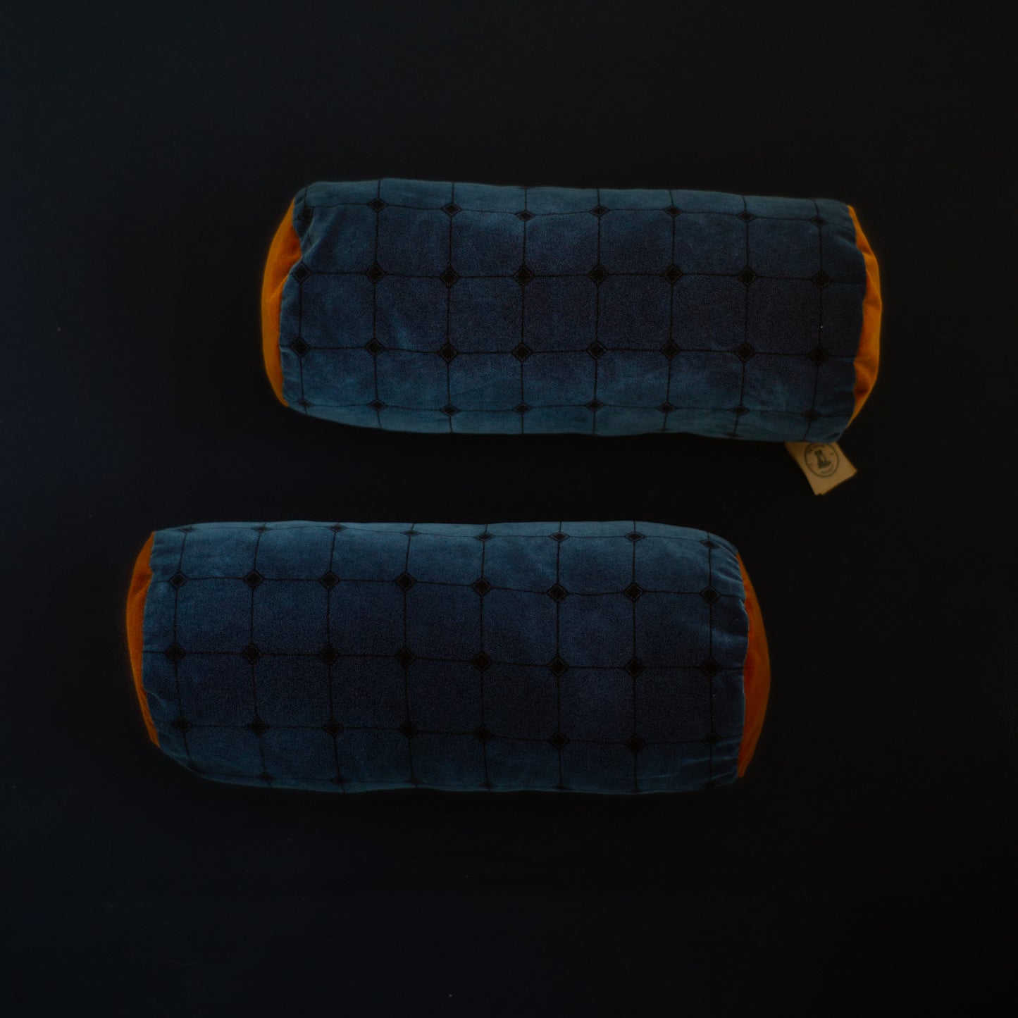 Two blue and orange velvet cylindrical pillows