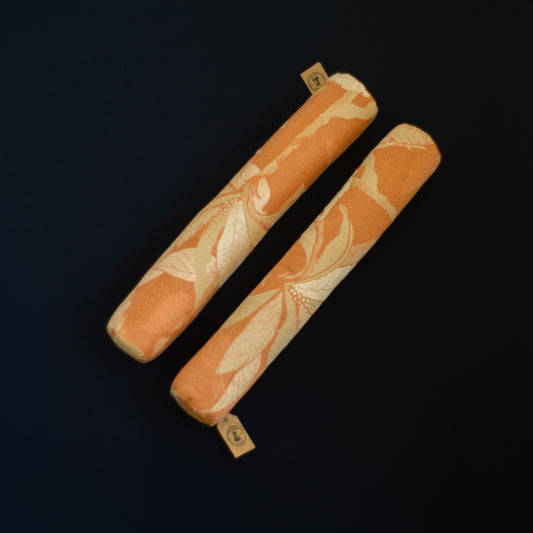 Two orange cylindrical cushions with floral patterns The Niche Society