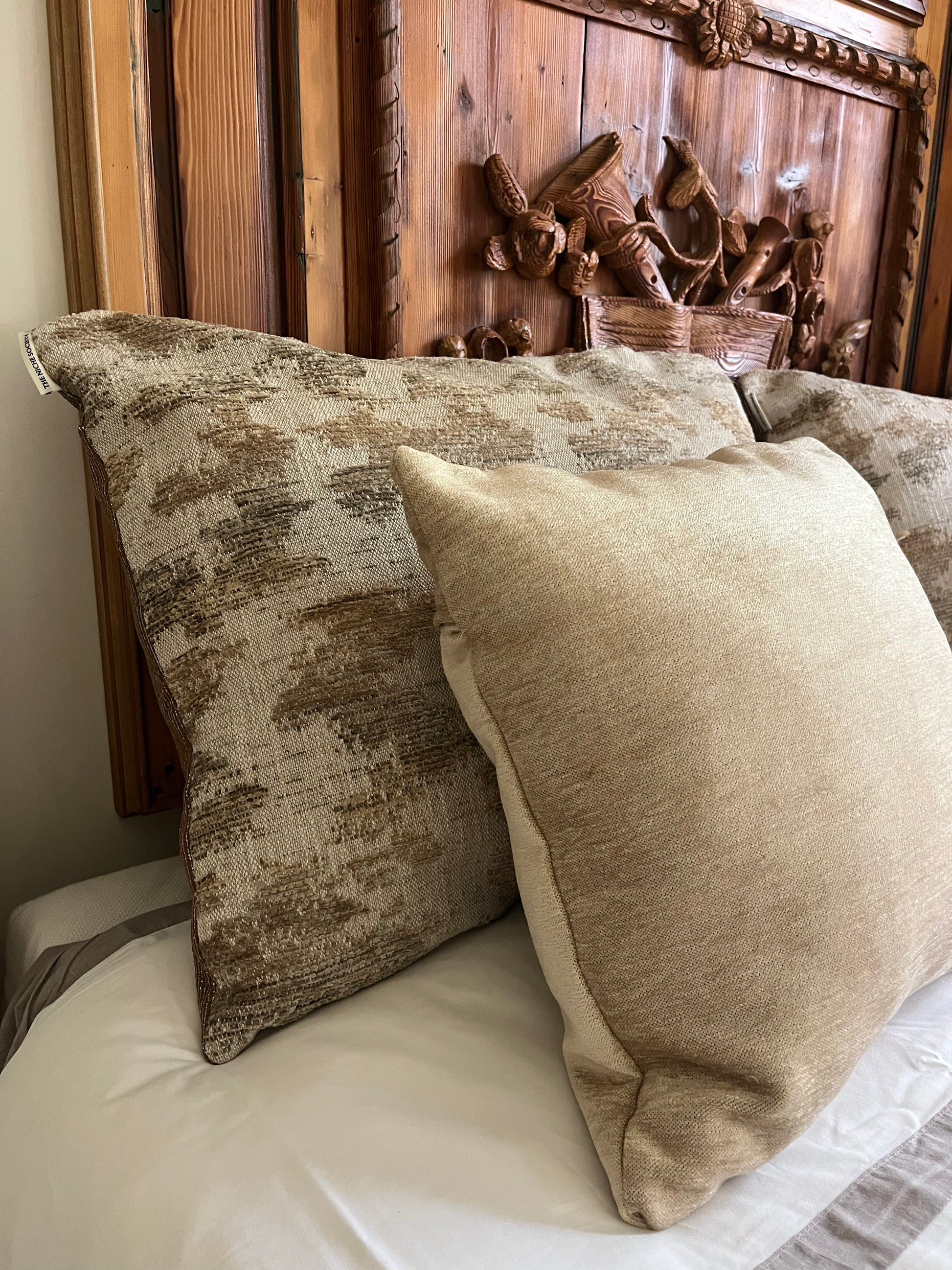 Decorative pillows on a bed with a wooden headboard featuring woven baskets.